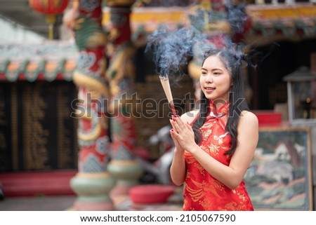 Woman lighting incense sticks to pay homage to Chinese New Year Royalty-Free Stock Photo #2105067590