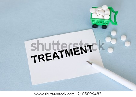 Treatment inscription on the card on a blue background next to the pen and tablets scattered, carzine for shopping with tablets