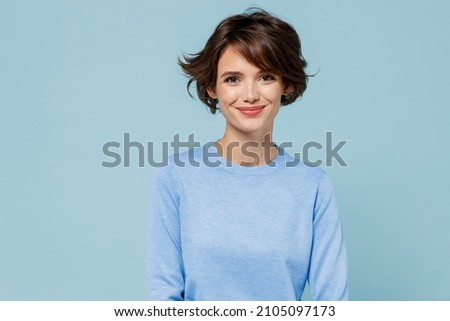 Young smiling fun happy caucasian european attractive cute woman 20s in casual sweater looking camera isolated on plain pastel light blue color background studio portrait. People lifestyle concept. Royalty-Free Stock Photo #2105097173