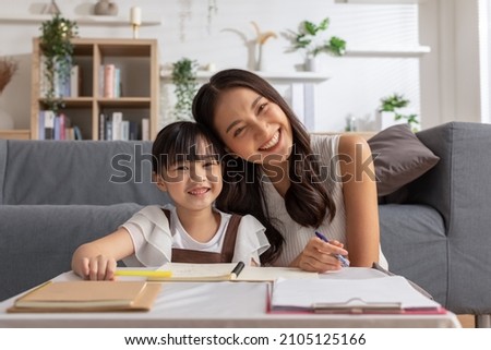 Happy asian young mother smile with daughter in living room at home. Asian young mother teaching small daughter to drawing reading and writing to develop her daughter skill. Home School Concept