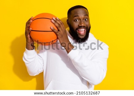 Photo of impressed young beard man play basketball wear white hoodie isolated on yellow color background