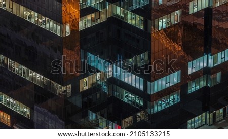 Windows in high-rise office building in the late evening with glowing and blinking interior lights timelapse. Aerial top view Royalty-Free Stock Photo #2105133215
