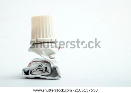 Empty aluminum ointment container tube, squeezed and rolled, side view macro Royalty-Free Stock Photo #2105137538