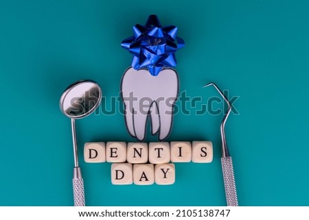Dentist day tooth and dental instruments
on a blue background.