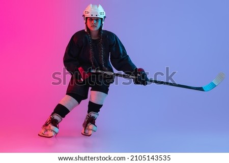 Giving a pass. Full-length image of little girl, professional hockey player, training isolated isolated over gradient pink purple background. Concept of team game, energy, sport, childhood, ad.