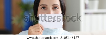 Portrait of young woman holding paper with painted smile. Good mood and positive concept