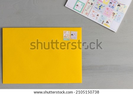 A yellow envelope with a pair of fun stamps stuck on it with no address next to many unused stamps.