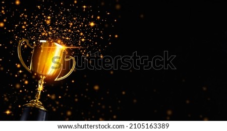 Champion golden trophy isolated on black background. Concept of success and achievement. Royalty-Free Stock Photo #2105163389
