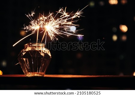 Bengal lights in glass jar against background of  busy night city. Festive sparklers at night. Royalty-Free Stock Photo #2105180525