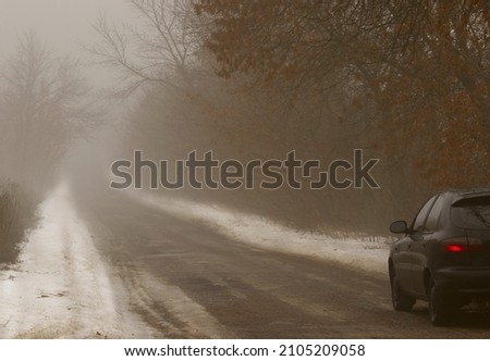 The car stands on the side of the road in the fog
