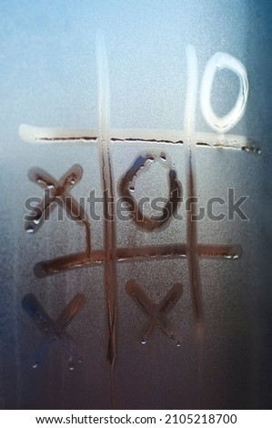 Tic-tac-toe is painted on the misted glass. The concept of loneliness during the coronavirus pandemic.