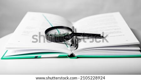 Magnifier over open business paper book. Concept of knowledge and studying.