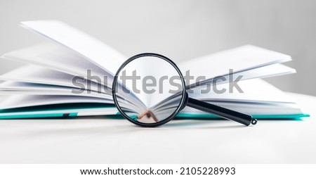 Magnifying glass over open business book. Concept of knowledge and getting information.