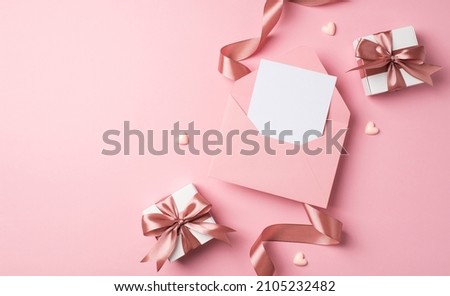 Top view photo of saint valentine's day decor two white gift boxes with pink bows small hearts curly silk ribbon and open pink envelope with letter on isolated pastel pink background with blank space