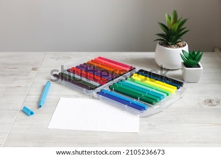 a box with felt-tip pens, two plastic pots with artificial succulents are on the table. Layout. Place for text Royalty-Free Stock Photo #2105236673