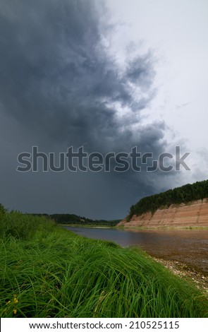  Ã?Â�Ã?Â¡urling storm cloud over the river bank. Vertical picture of landscape with coming nearer thunder-storm.
