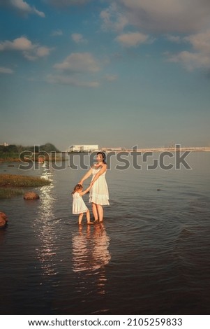 family mom and daughter of different nationalities dancing in water of sea, copy space, life style
