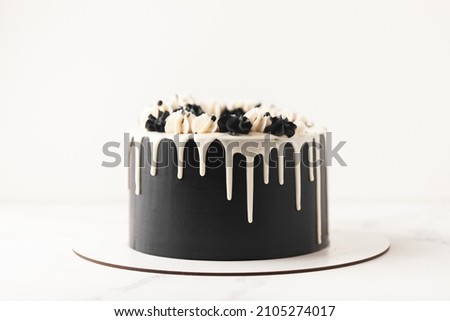 Birthday cake with black cream cheese frosting and white chocolate drips on the white background