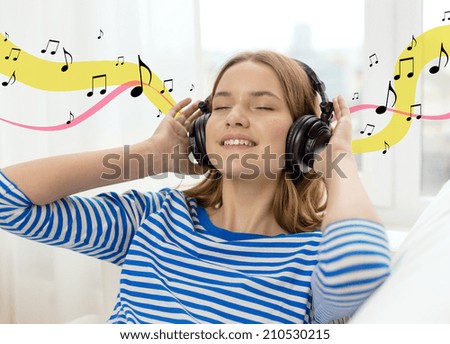 technology, music and happiness concept - smiling young girl in headphones at home