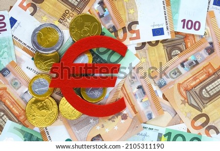 Red felt Euro currency symbol and gold chocolate euro cents on 50 and 100 euro banknotes background. European currency. Financial, bank, money, economy, business concept. Place for text, top view.