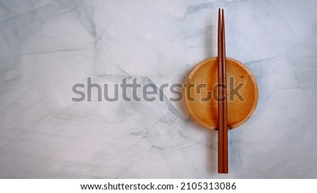 Wooden kitchenware that gives a classic and minimalist impression. Food and drink concept. Food Photography. Flat Lay, Wooden Chopsticks and bowl on the table. Space for text. Blue Pattern Background.