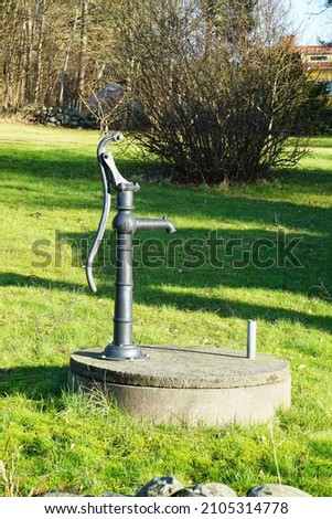 An old fashioned outdoor water hand pump in garden