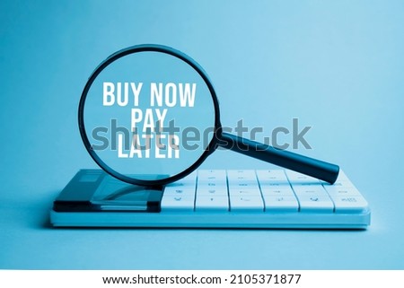 Finance and business concept. On a white background lies a calculator and a magnifying glass with the inscription - BUY NOW PAY LATER Royalty-Free Stock Photo #2105371877