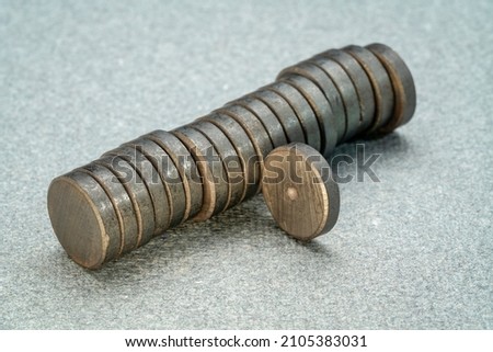 stack of small round ceramic ferrite magnets on textured gray  paper Royalty-Free Stock Photo #2105383031