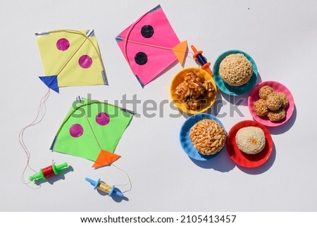 Makar sankranti greetings wish poster with kites . Uttarayan festive food concept with Indian traditional sweets assorted type of laddus til, peanut, puffed rice, til mawa ladoo, Rajgira Royalty-Free Stock Photo #2105413457