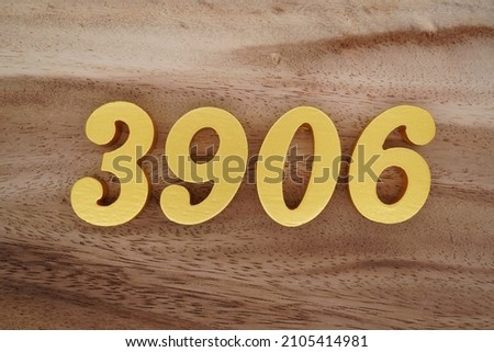 Golden Arabic numerals 3906 on a dark brown to white wood grain background.