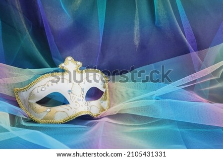 Photo of elegant and delicate Venetian mask over blue chiffon background