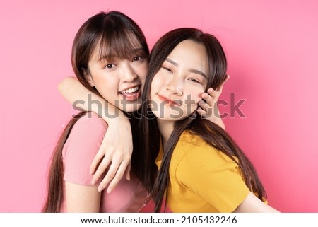 Two young Asian women on pink background Royalty-Free Stock Photo #2105432246