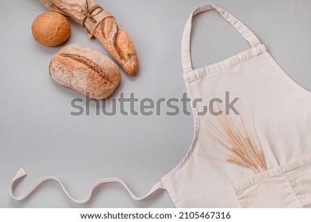 Apron mockup, with artisan bread and rye on a gray background. craft bakery concept. flat lay, top view.  Royalty-Free Stock Photo #2105467316