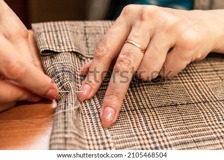 The dressmaker will open the fabric for the future costume for further work. Fashion designer tailor in the workshop of the studio, developing a new collection of clothes. 