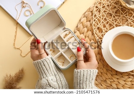 Female hands with beautiful manicure holding jewelry box on color background Royalty-Free Stock Photo #2105471576