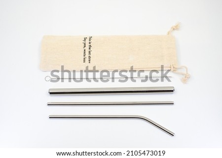Metallic reusable straw kit with sustainable linen pouch bag on white background Royalty-Free Stock Photo #2105473019