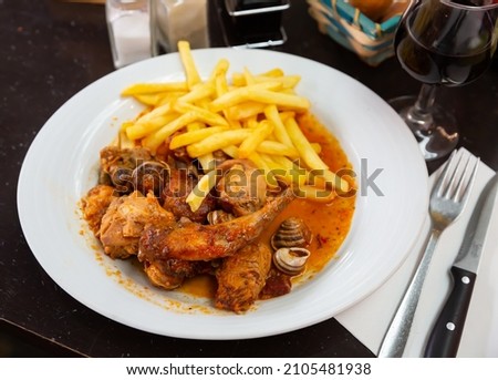 Picture of tasty stewed in sause rabbit with snails, served with french fries at plate