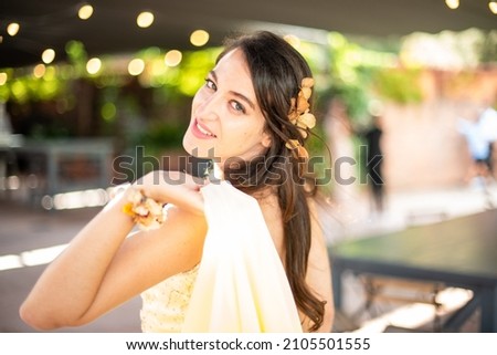 Wedding guest smiling at camera. Young woman with flowers on her head and yellow dress possing. Royalty-Free Stock Photo #2105501555