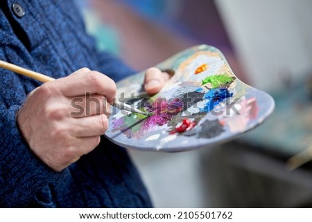 Closeup artist hand painting palette acrylic colour paint brush in art studio indoors