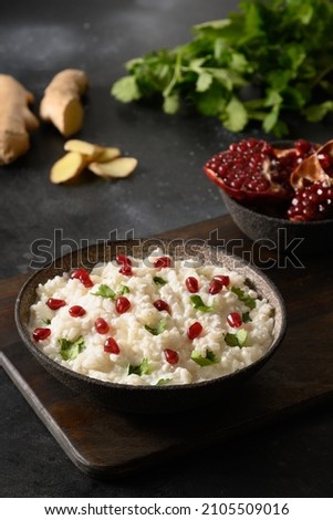 Curd Rice with pomegranate, cilantro, ginger on a black background. Indian dinner. Close up. Royalty-Free Stock Photo #2105509016