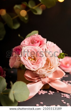 A bouquet of delicate pink roses in a box. Festive vertical card with pink flowers on a dark background, copy space for text
