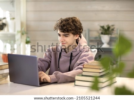 young man, student studying at home, looking at a laptop Royalty-Free Stock Photo #2105521244