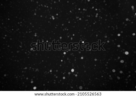 photo of real falling medium sized snowflakes out of focus on black background for overlay blending mode. night scene. new year and merry christmas decoration idea.
