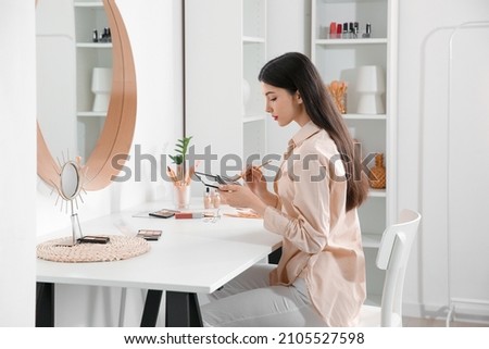 Beautiful young woman with brush and eyeshadows palette in dressing room Royalty-Free Stock Photo #2105527598