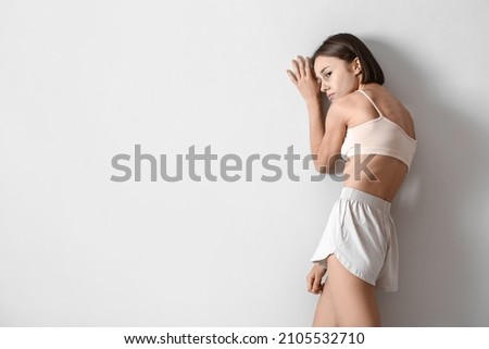 Young skinny woman on light background. Anorexia concept Royalty-Free Stock Photo #2105532710