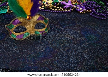 Mardi Gras Mask and colorful Mardi Gras Beads Background Royalty-Free Stock Photo #2105534234