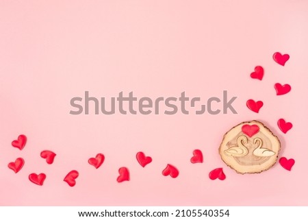 Valentine's Day background Wooden swans and red hearts confetti on pastel pink background.. Valentines day concept. Flat lay, top view, copy space