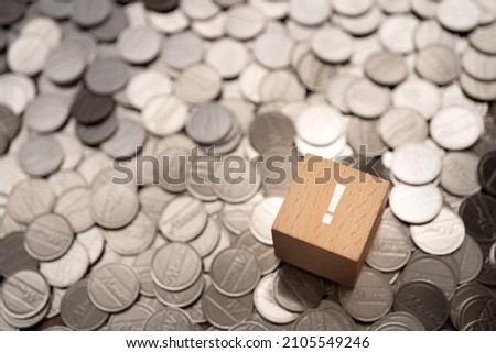 A wooden block with an exclamation mark and coins.