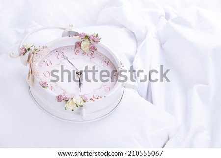 Metal clock on pillows on a big white bed