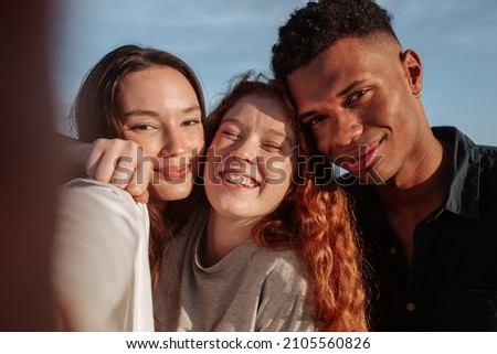Multicultural friends taking a group selfie together. Gen Z friends posing for the camera while hanging out together on a sunny day. Group of young people making happy memories together.